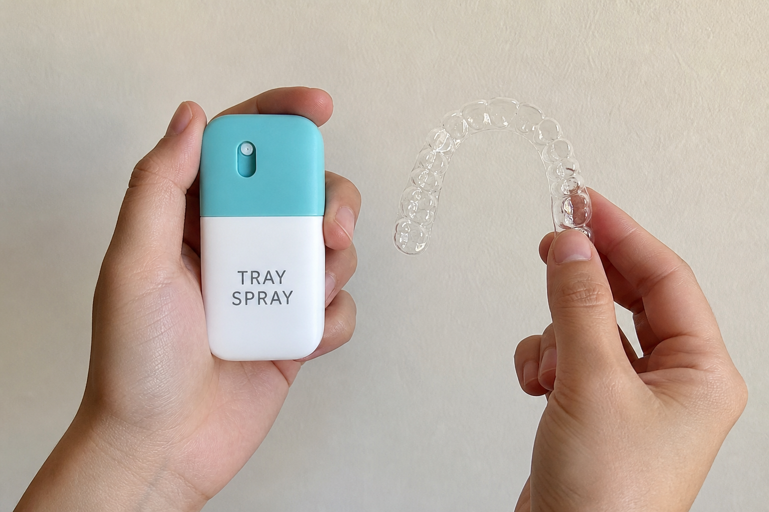 Hands holding a Tray Spray and a clear aligner